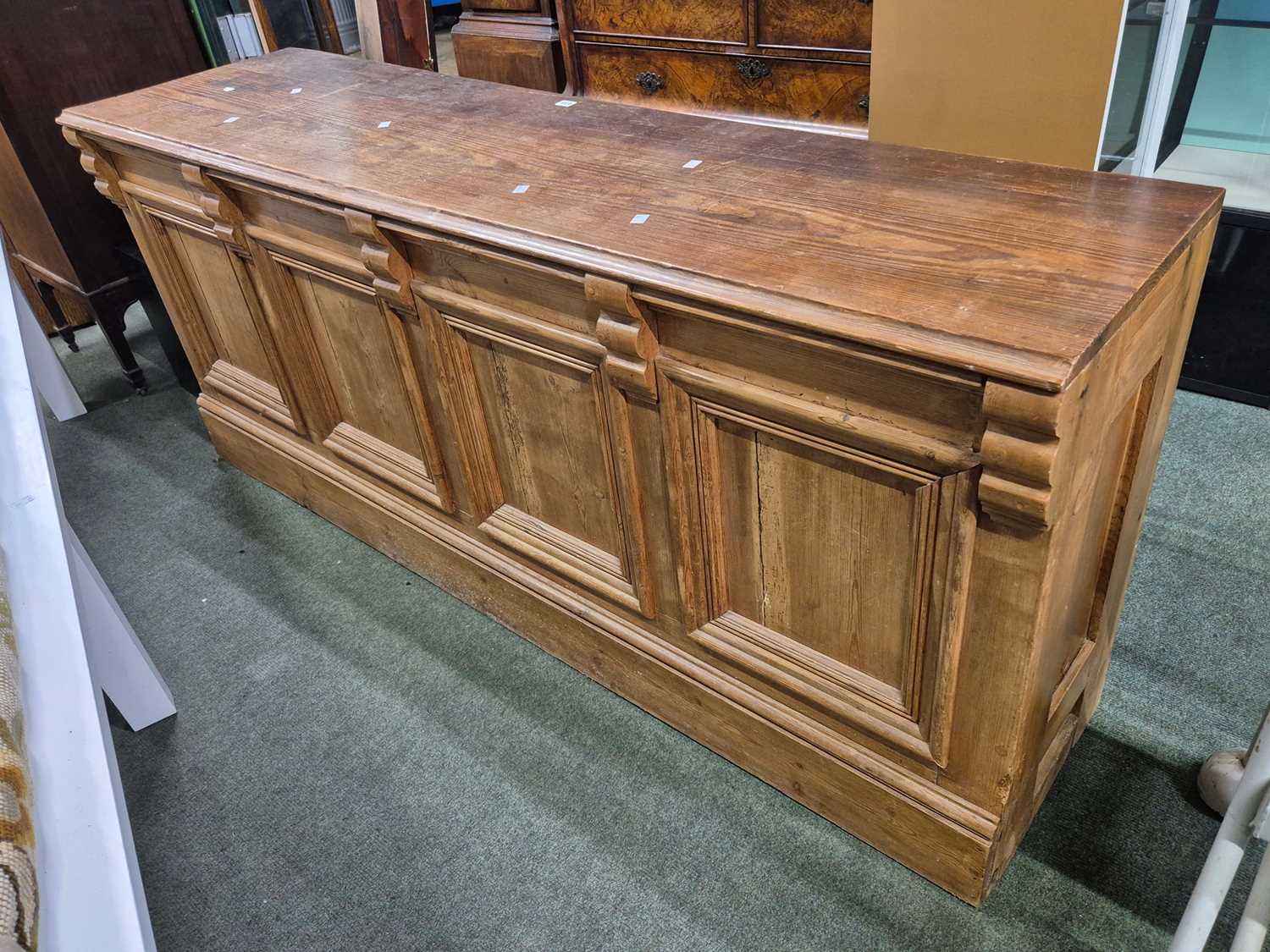 Lot 473 - A pine shop counter with three drawers over an...