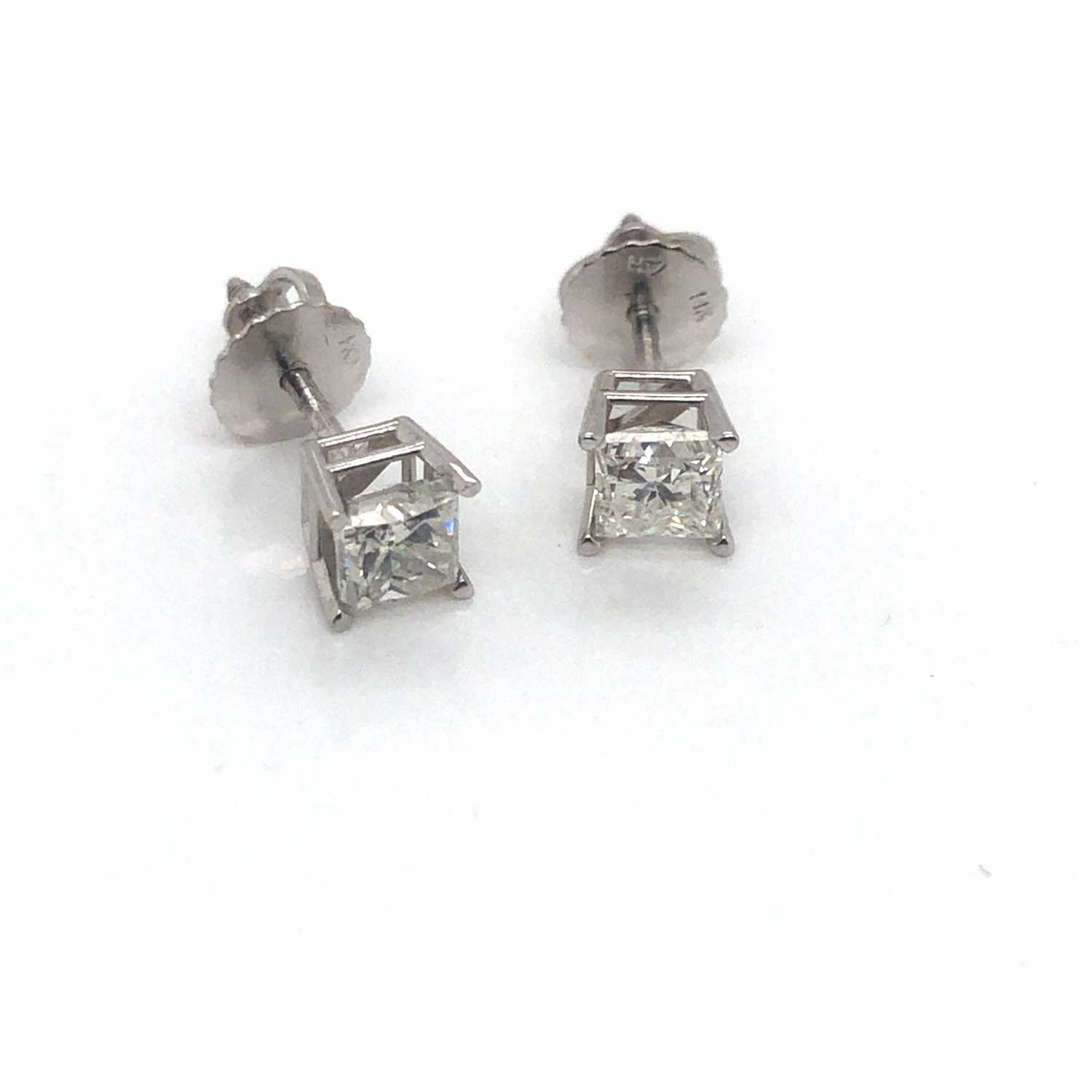 Lot 16 - A pair of princess-cut diamond stud earrings...