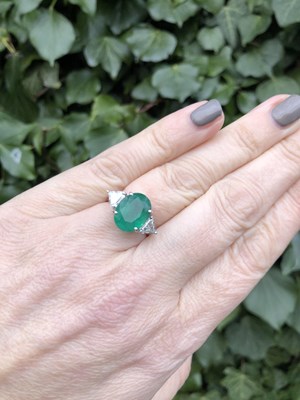 Lot 66 - An emerald and diamond ring. The central oval...