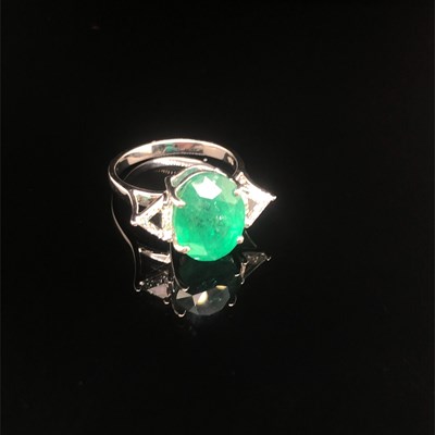 Lot 66 - An emerald and diamond ring. The central oval...