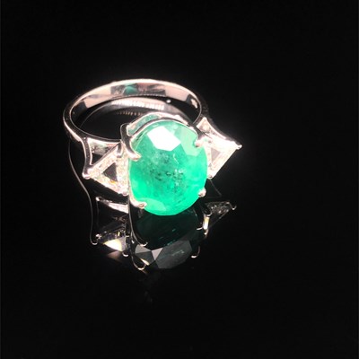 Lot 66 - An emerald and diamond ring. The central oval...