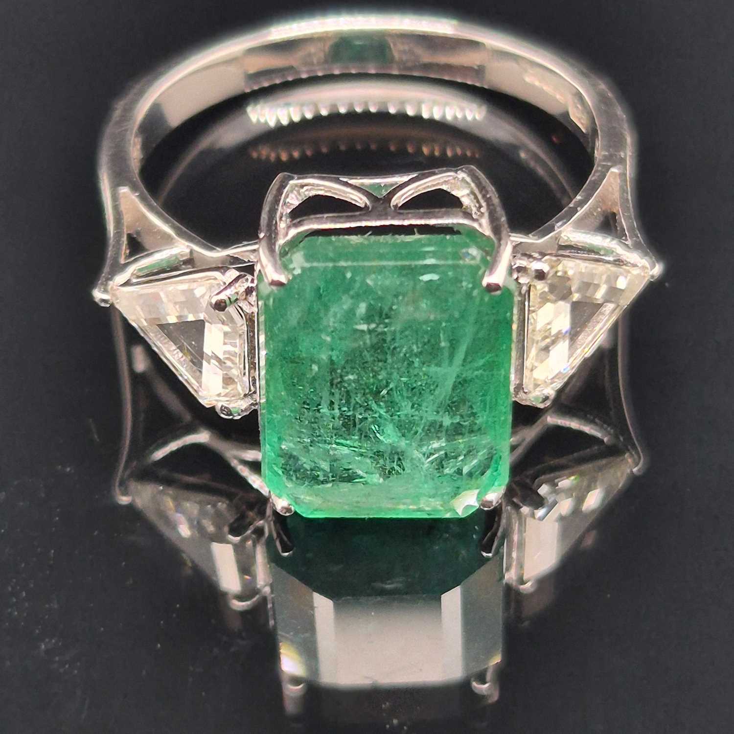Lot 60 - An 18ct hallmarked white gold, emerald and...