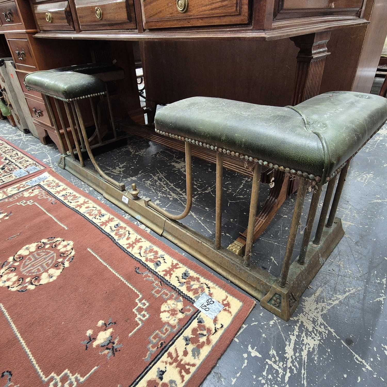 Lot 2246 - An antique leather-topped brass club fender....