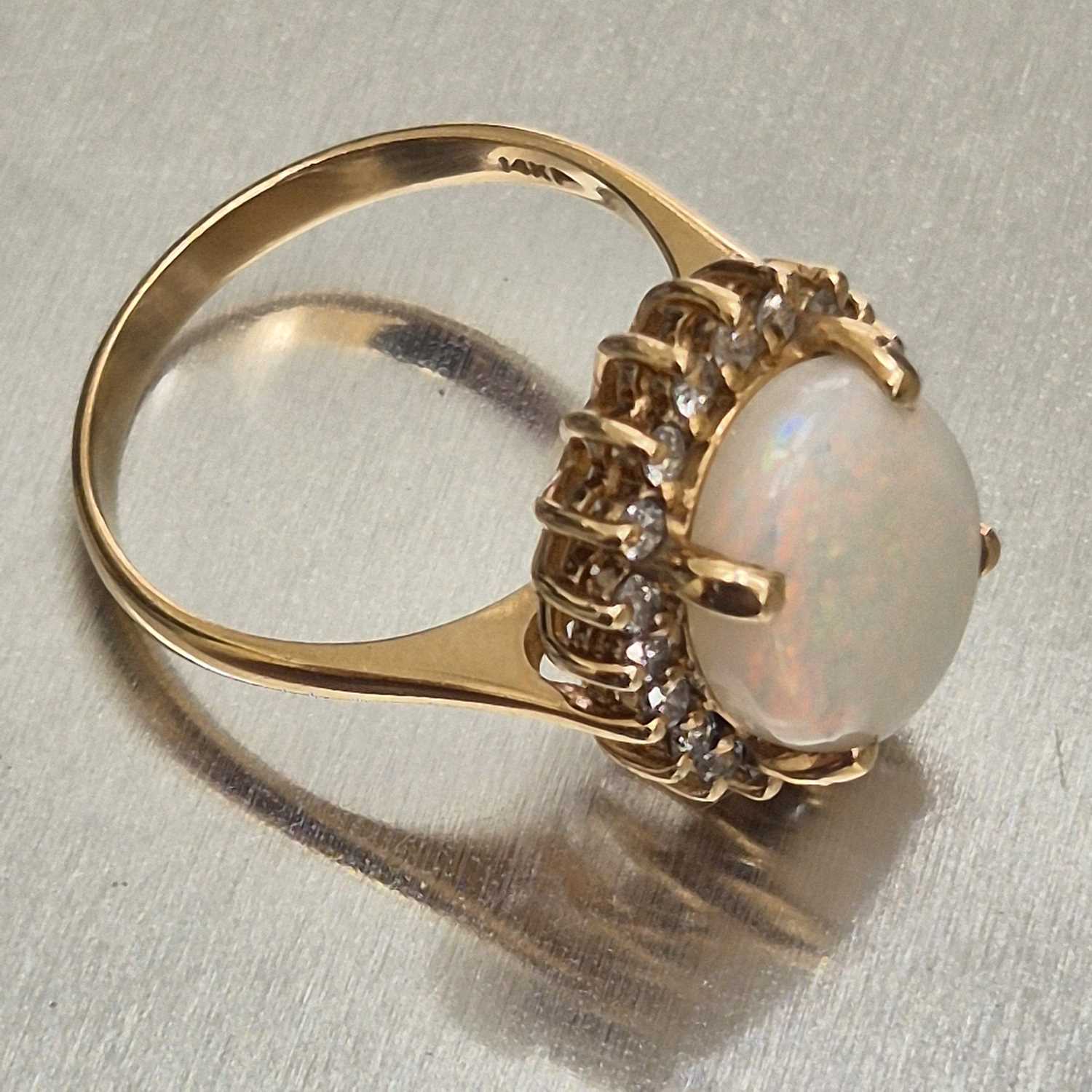 Lot 45 - An opal and diamond oval cluster ring. The...