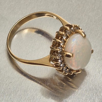 Lot 45 - An opal and diamond oval cluster ring. The...