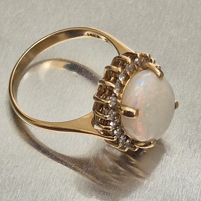 Lot 45 - An opal and diamond oval cluster ring. The...