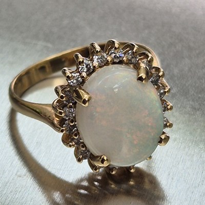 Lot 45 - An opal and diamond oval cluster ring. The...
