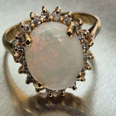 Lot 45 - An opal and diamond oval cluster ring. The...