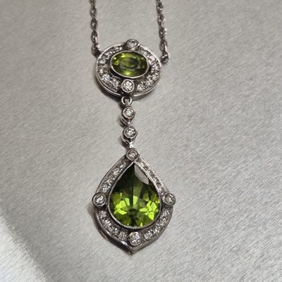 Lot 56 - A peridot and diamond pendant. The pear-shaped...