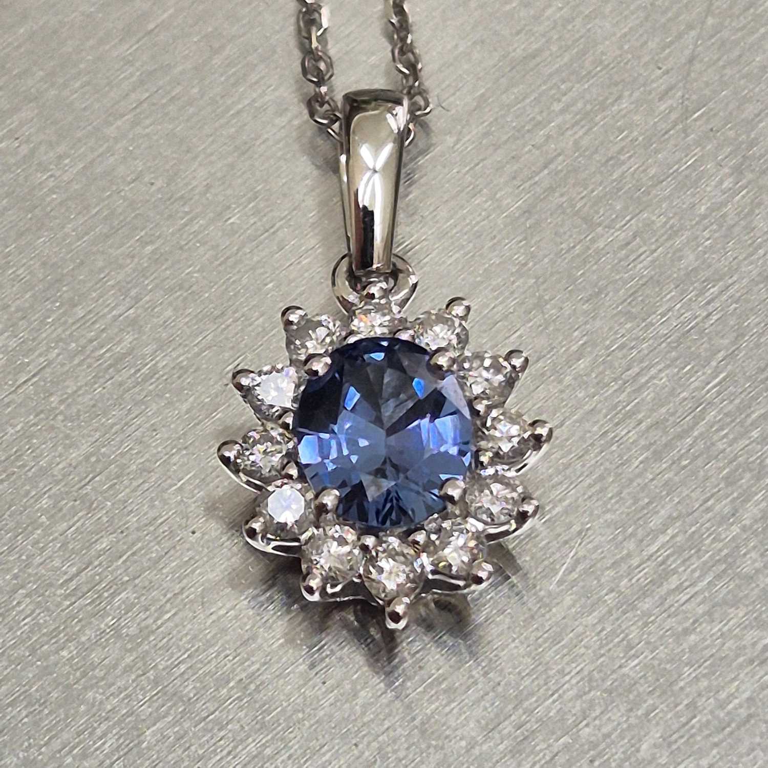 Lot 61 - A sapphire and diamond oval cluster pendant...