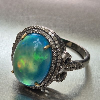 Lot 72 - An opal and diamond cluster ring. The oval...