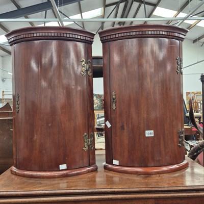 Lot 1040 - A pair of mahogany bow front corner cabinets.