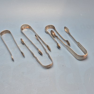 Lot 124 - Three George III silver sugar tongs by George...