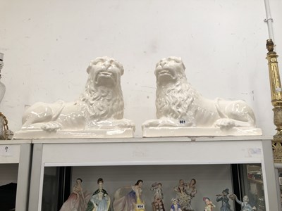 Lot 861 - A pair of white glazed pottery reclining lions