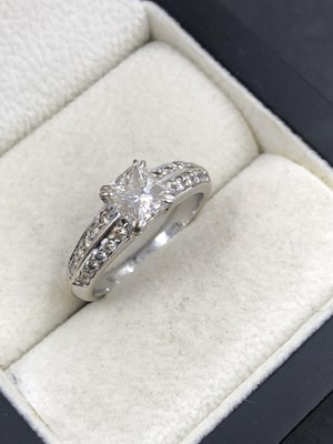 Lot 512 - A princess-cut diamond solitaire ring with two...