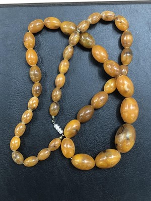 Lot 524 - A vintage graduated row of oval amber coloured...