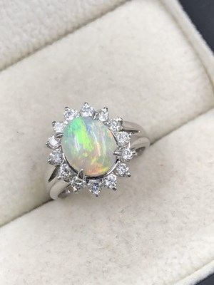 Lot 520a - A cabochon oval opal with a halo of round...
