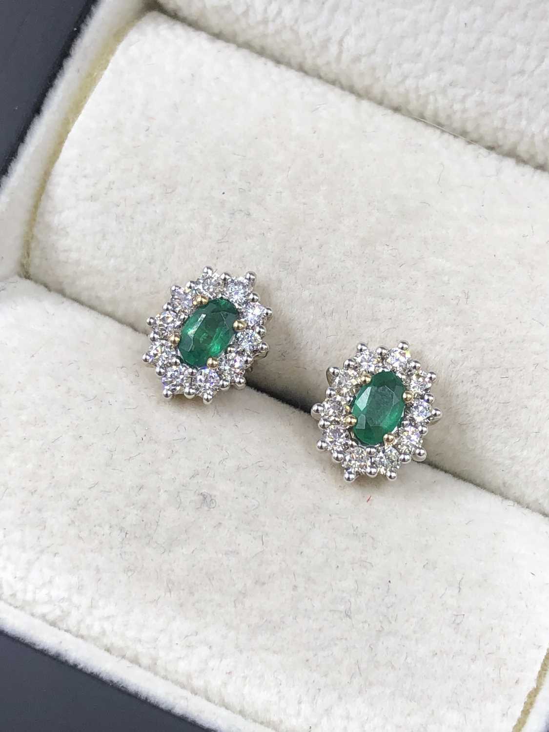 Lot 555 - A pair of oval emerald and round brilliant cut...