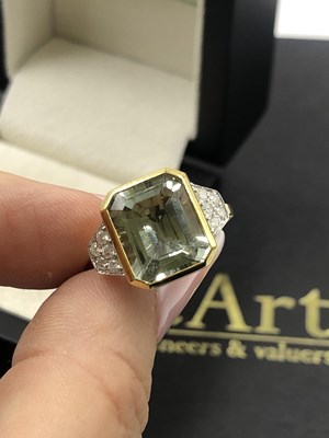 Lot 565c - A step-cut green amethyst flanked by round...