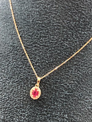 Lot 570b - An 18ct hallmarked gold oval ruby and diamond...
