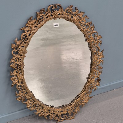 Lot 1604 - An oval mirror within a pierced and foliate...