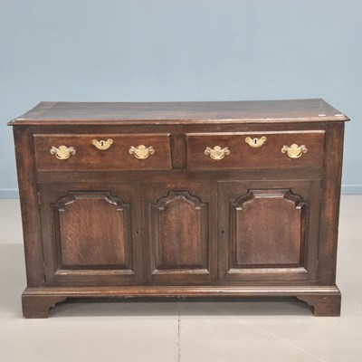 Lot 1393 - A Georgian oak dresser base with an arch panel...