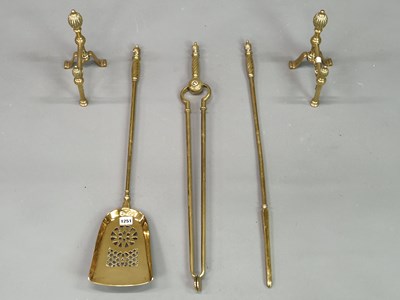 Lot 1251 - A set of three brass fire irons, fire dogs and...