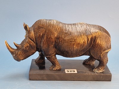 Lot 529 - A bronze figure of a rhinoceros walking on a...