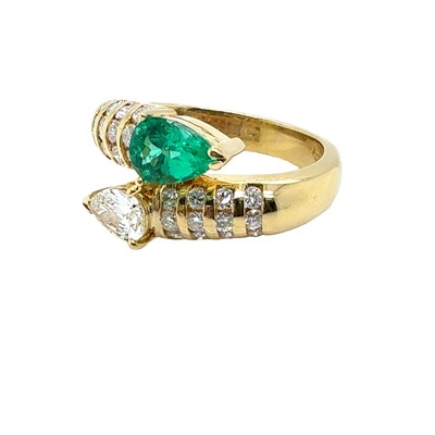 Lot 13 - An emerald and diamond set crossover ring. The...