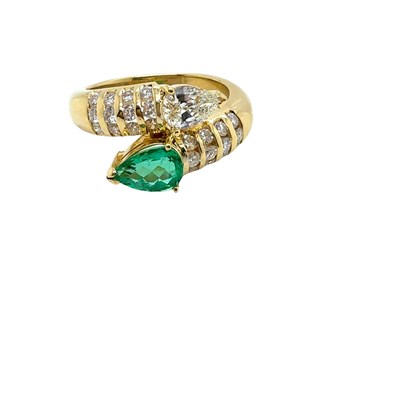 Lot 13 - An emerald and diamond set crossover ring. The...