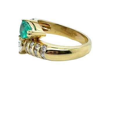 Lot 13 - An emerald and diamond set crossover ring. The...