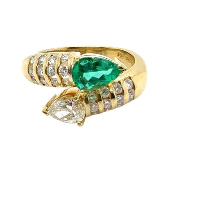 Lot 13 - An emerald and diamond set crossover ring. The...