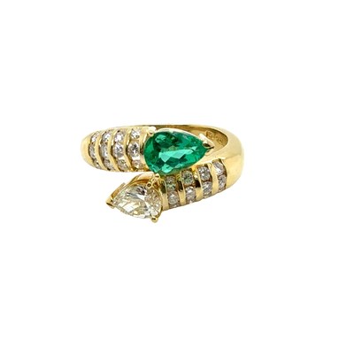 Lot 13 - An emerald and diamond set crossover ring. The...
