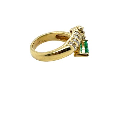 Lot 13 - An emerald and diamond set crossover ring. The...
