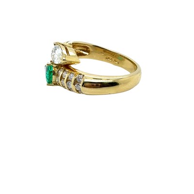 Lot 13 - An emerald and diamond set crossover ring. The...