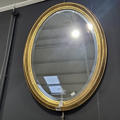 Lot 1561 - A large oval gilt framed wall mirror.