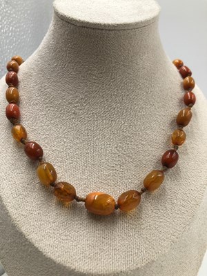 Lot 1030 - Two vintage amber coloured bead necklaces, the...