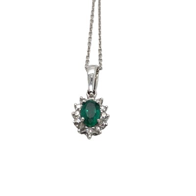 Lot 1033 - A 9ct white gold oval emerald and round...