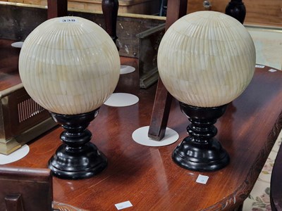 Lot 338 - A pair of bone spheres on ebonised stands