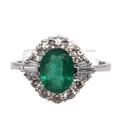 Lot 1010 - An oval emerald and diamond cluster ring....