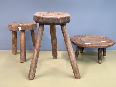 Lot 1556 - Three various oak milking stools, the tallest...