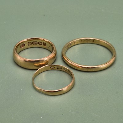 Lot 1033 - Three 22ct hallmarked gold wedding rings,...