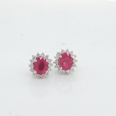 Lot 1048 - A pair of 18ct white gold oval ruby and round...