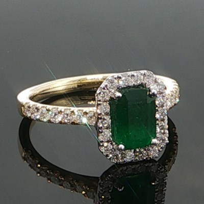 Lot 1064 - An 18ct white and yellow gold step cut emerald...