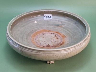 Lot 1044 - A shallow Chinese celadon bowl incised with a...