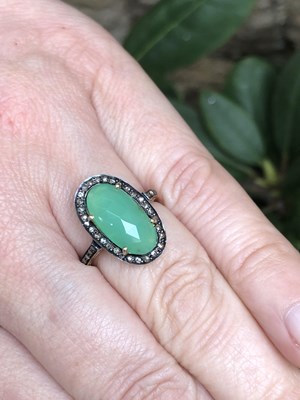 Lot 1103 - A dress ring set with a central chrysoprase...
