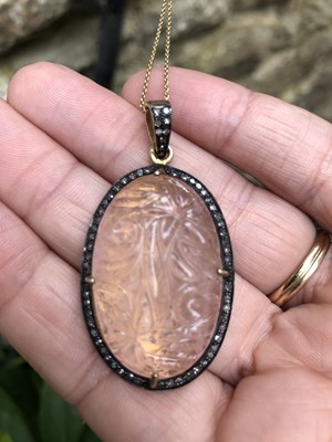 Lot 1102 - A large hand-carved rose quartz pendant with a...