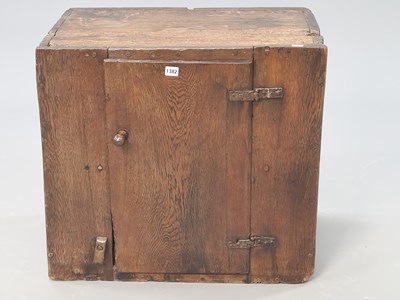 Lot 1382 - A 17th century oak cupboard, the plank door...