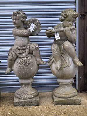 Lot 480 - Two cast stone cherub figures playing musical...