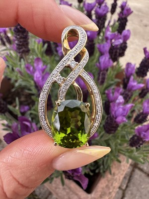 Lot 1042 - A peridot and diamond pendant, claw set with a...